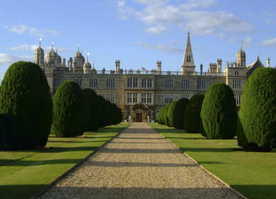 A gravel driveway leads the eye past lawns and topiary towards the south entrance of Burghley House. Burghley House is the largest and grandest of the first Elizabethan Age. It was built between 1555 and 1587 by William Cecil, Lord Treasurer to Queen Elizabeth I. The formal gardens and surrounding parkland were created by Capability Brown in 1775-80., Near Stamford, Lincolnshire, England.